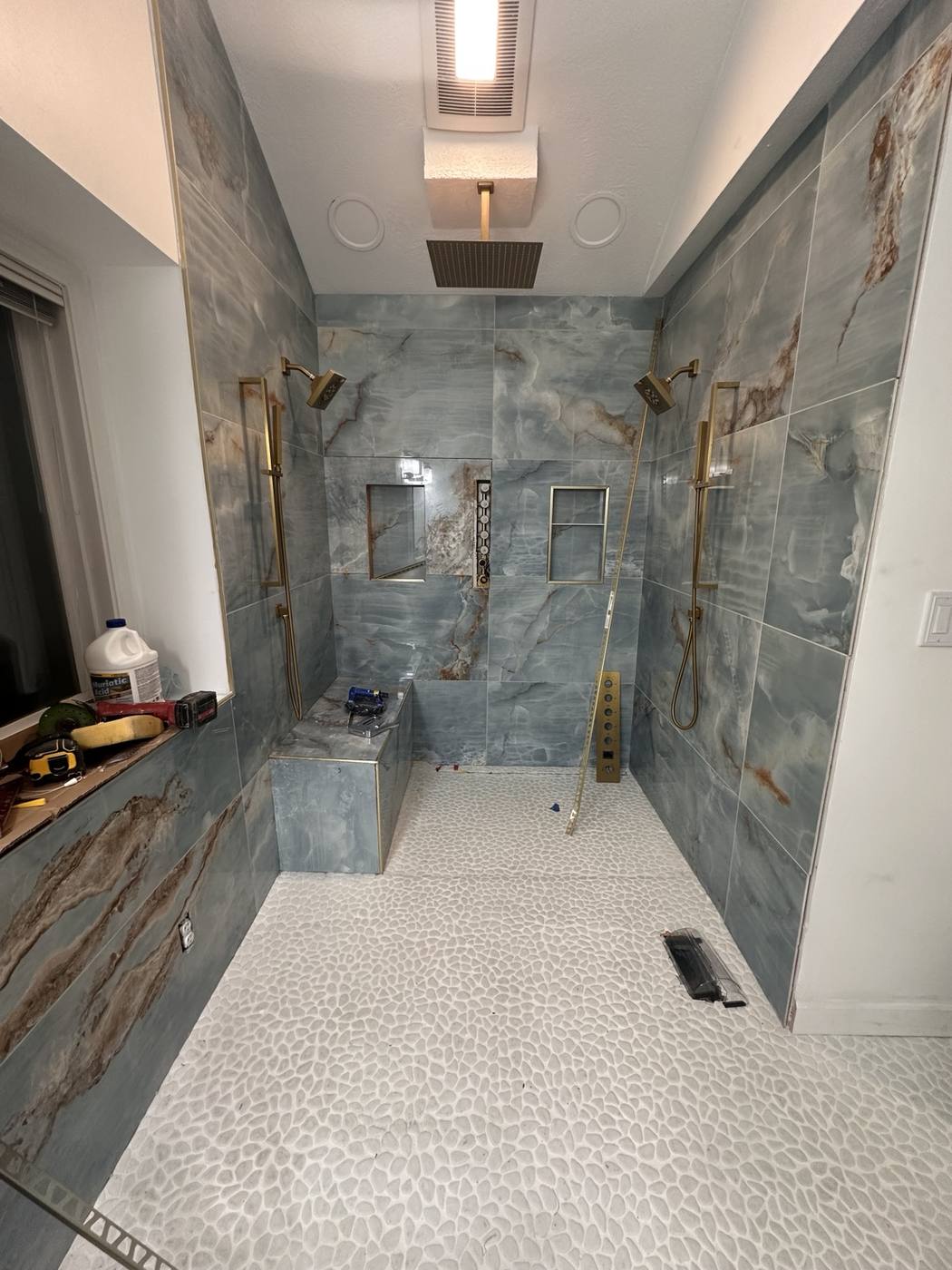 Full custom shower with rain head, handheld fixtures, bench and pebble floor